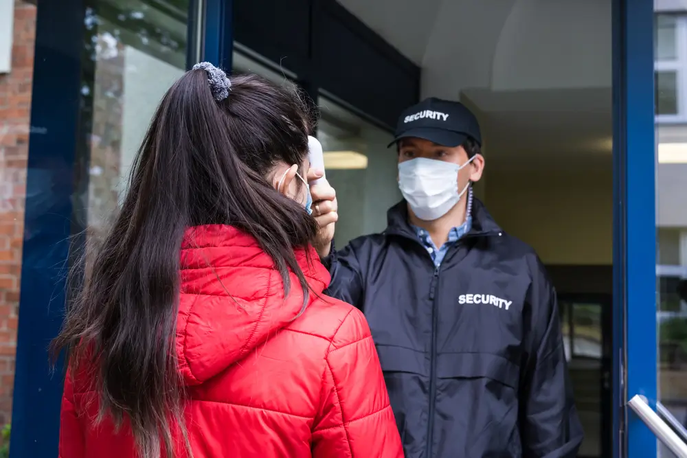 a hospital security guard checking a person at a hospital gate